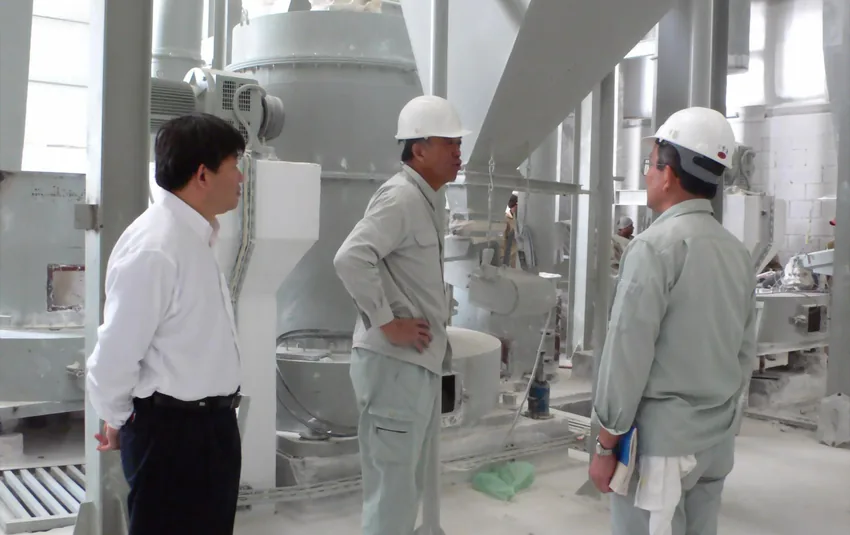 Malaysian visitors discussing grinding machinery in the workshop